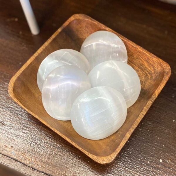 selenite palm stones in a wooden bowl